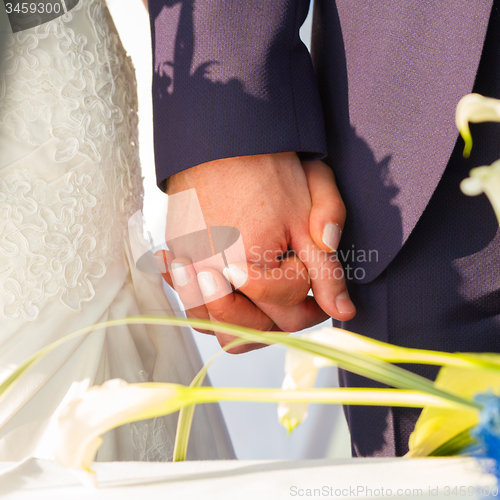 Image of Wedding couple holding hands.