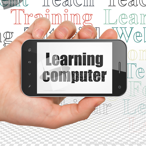 Image of Studying concept: Hand Holding Smartphone with Learning Computer on display