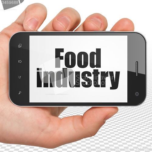 Image of Manufacuring concept: Hand Holding Smartphone with Food Industry on display