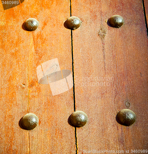 Image of nail dirty stripped paint in the brown wood door and rusty yello