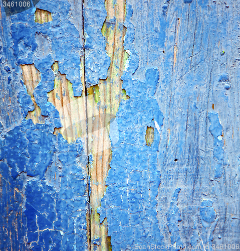 Image of dirty stripped paint in the blue wood door and rusty nail