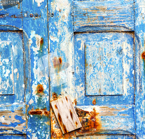 Image of stripped paint in the blue wood door and rusty nail