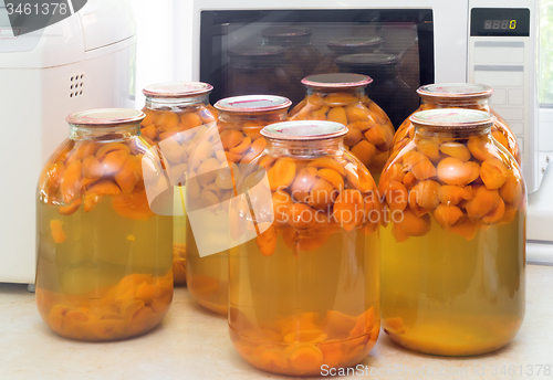 Image of Home canning: large glass cylinders with apricot compote.