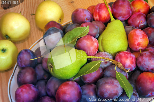 Image of Fruit in a ceramic dish on a wooden table.