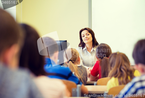 Image of group of school kids raising hands in classroom