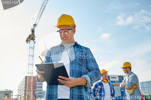 Image of builder in hardhat with clipboard at construction