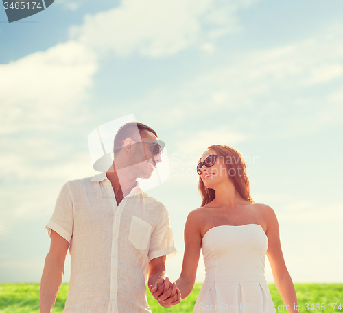 Image of smiling couple in sunglasses walking outdoors