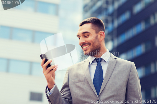Image of smiling businessman with smartphone outdoors