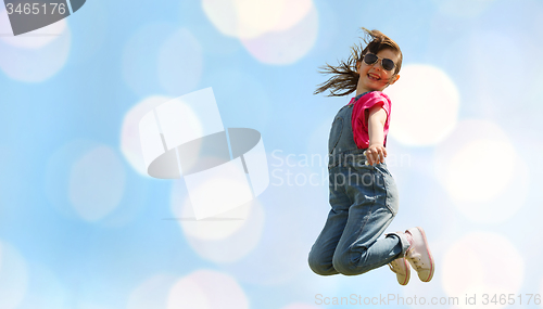 Image of happy little girl jumping high over blue lights