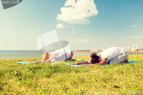 Image of couple making yoga exercises outdoors