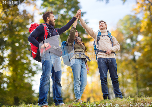 Image of happy friends with backpacks making high five