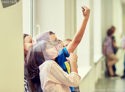 Image of group of school kids taking selfie with smartphone