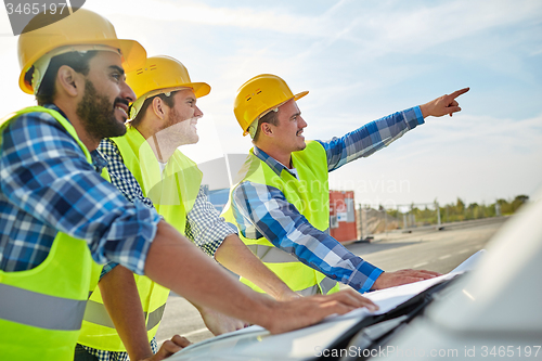 Image of close up of builders with blueprint on car hood