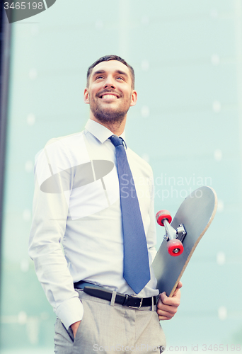 Image of young smiling businessman with skateboard outdoors