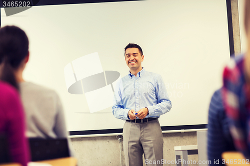 Image of group of students and smiling teacher in classroom