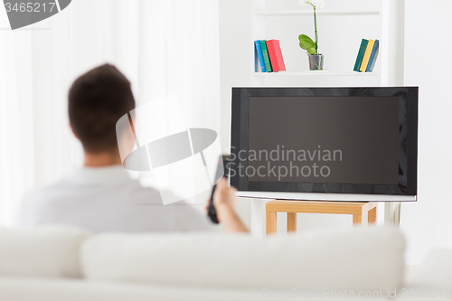 Image of man watching tv and changing channels at home