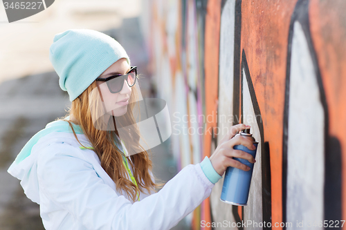 Image of teenage girl drawing graffiti with spray paint