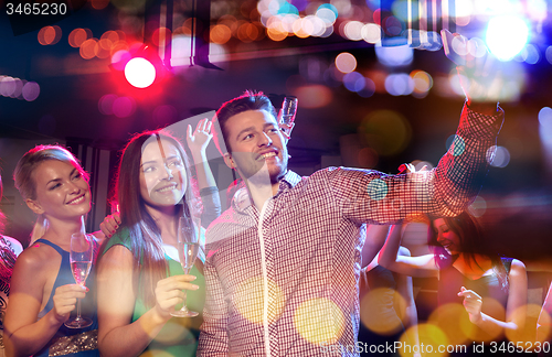 Image of friends taking selfie by smartphone in night club