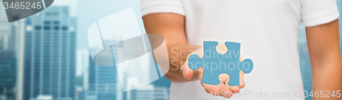 Image of man holding blue puzzle piece over city background