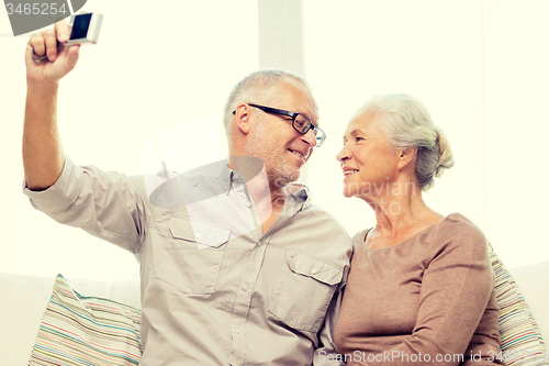 Image of happy senior couple with camera at home