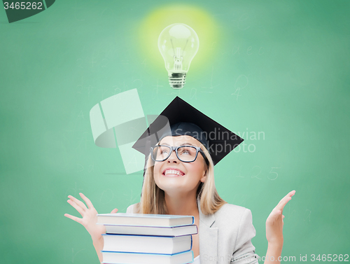 Image of happy student girl in bachelor cap with books