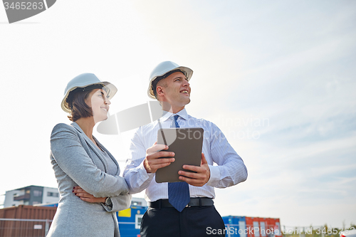 Image of happy builders in hardhats with tablet pc outdoors