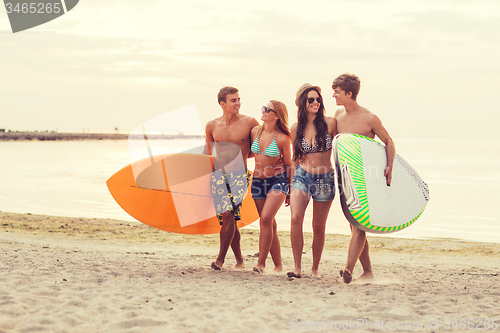 Image of smiling friends in sunglasses with surfs on beach