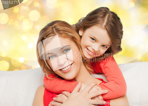 Image of happy mother and daughter hugging over lights