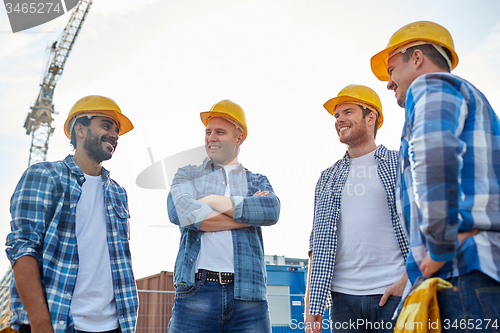 Image of group of smiling builders in hardhats outdoors