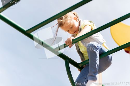 Image of happy little girl climbing on children playground