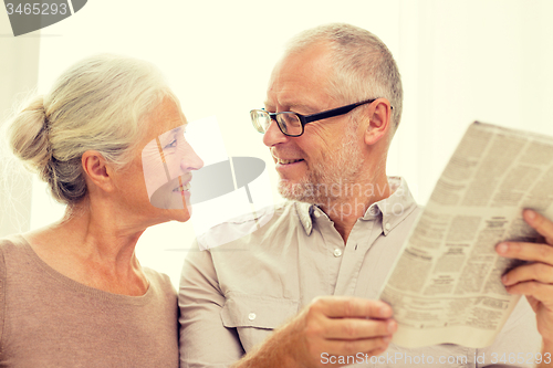 Image of happy senior couple reading newspaper at home