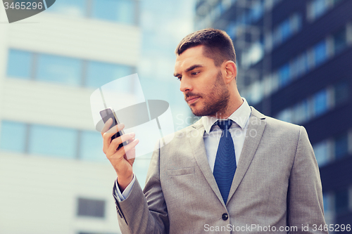 Image of serious businessman with smartphone outdoors