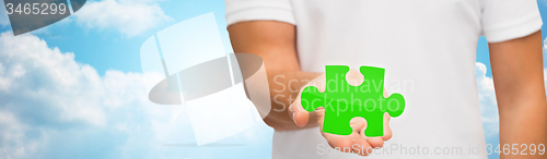 Image of man holding green puzzle over sky background