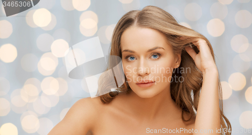 Image of beautiful young woman face over holidays lights