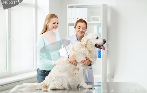 Image of happy woman with dog and doctor at vet clinic