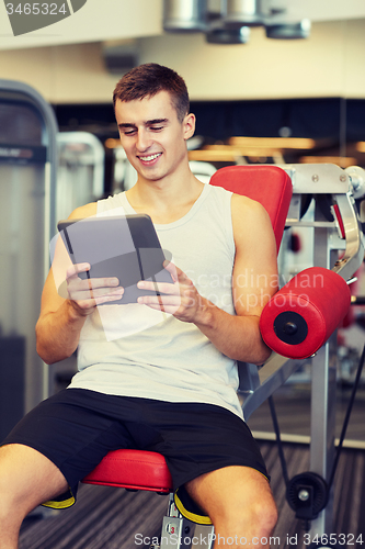 Image of smiling young man with tablet pc computer in gym