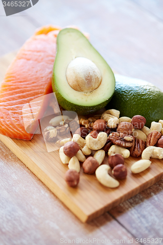 Image of close up of salmon, avocado and nuts on table
