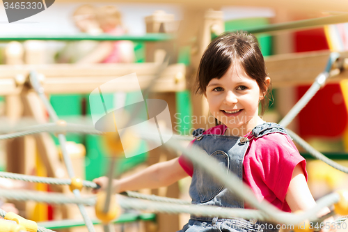Image of happy little girl climbing on children playground