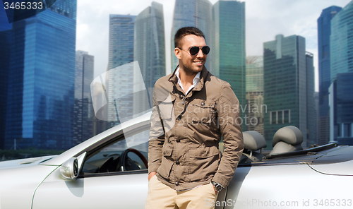 Image of happy man near cabriolet car over city background