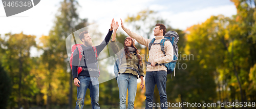 Image of happy friends with backpacks making high five