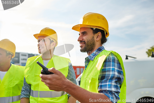 Image of happy male builders in vests with walkie talkie