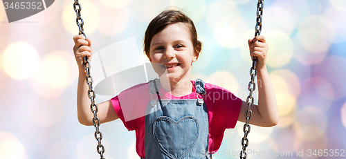 Image of happy little girl swinging on swing over lights