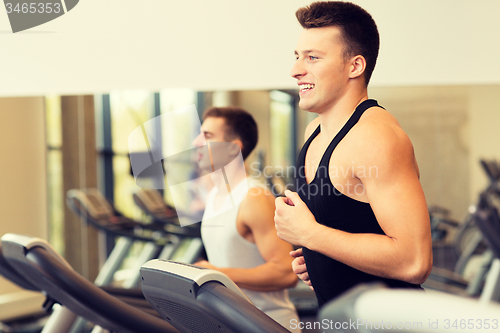 Image of smiling men exercising on treadmill in gym