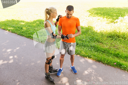 Image of happy couple with roller skates riding outdoors