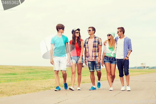 Image of group of smiling teenagers walking outdoors