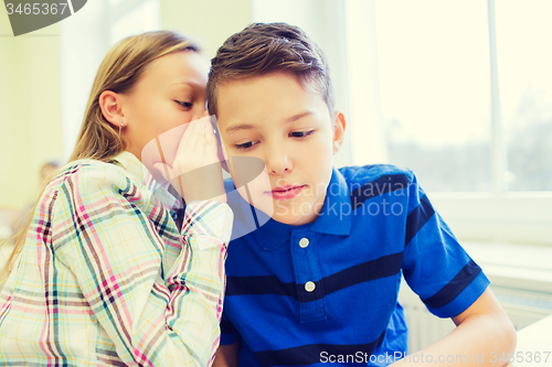 Image of smiling schoolgirl whispering to classmate ear