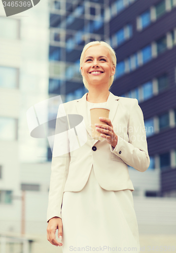Image of smiling businesswoman with paper cup outdoors