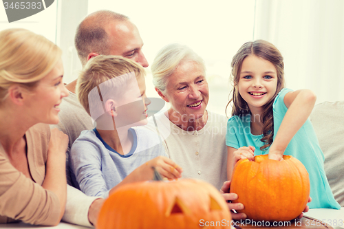 Image of happy family sitting with pumpkins at home