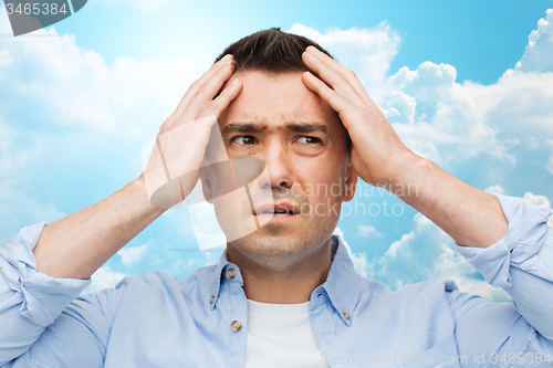 Image of unhappy man with closed eyes touching his forehead