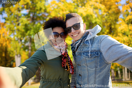 Image of happy teenage couple taking selfie on city street